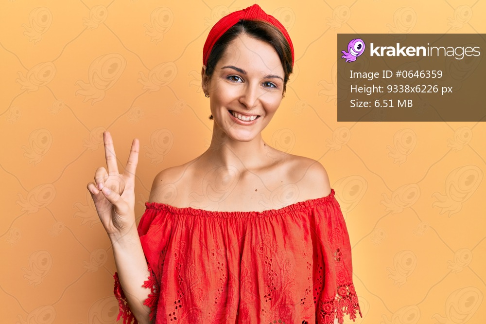 Young brunette woman with short hair wearing casual clothes smiling with happy face winking at the camera doing victory sign. number two. 