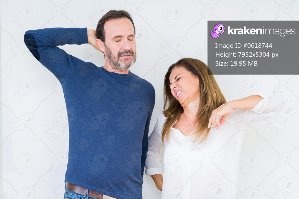 Beautiful middle age couple in love over isolated background stretching back, tired and relaxed, sleepy and yawning for early morning