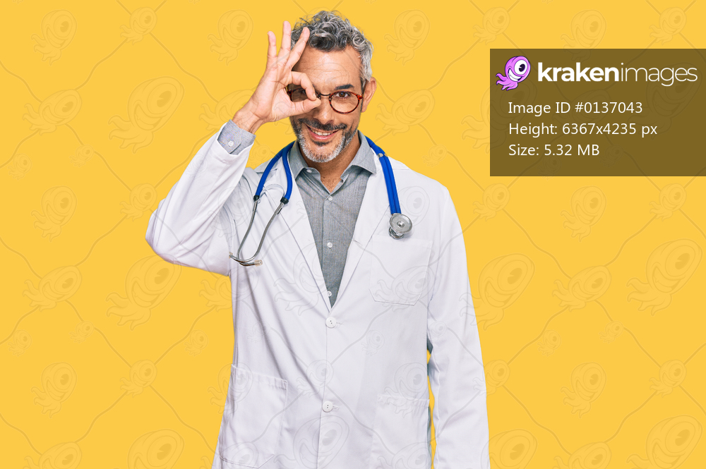 Middle age grey-haired man wearing doctor uniform and stethoscope smiling happy doing ok sign with hand on eye looking through fingers 