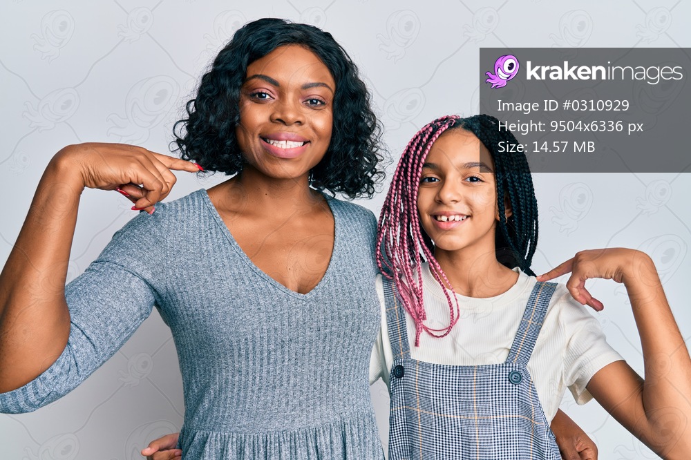 Beautiful african american mother and daughter wearing casual clothes and hugging looking confident with smile on face, pointing oneself with fingers proud and happy. 