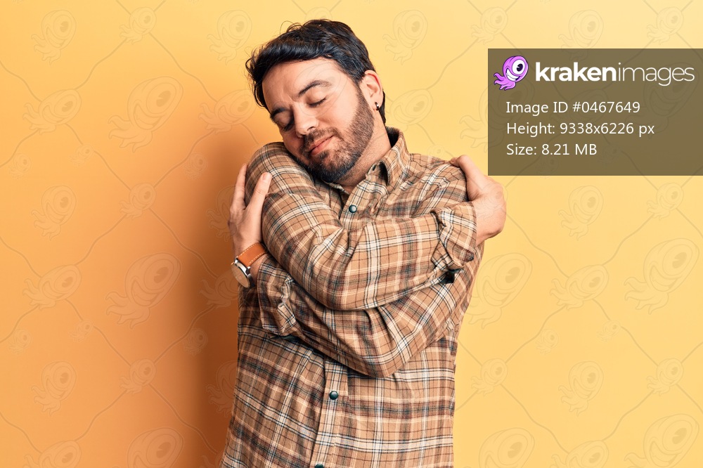 Young hispanic man wearing casual clothes hugging oneself happy and positive, smiling confident. self love and self care 