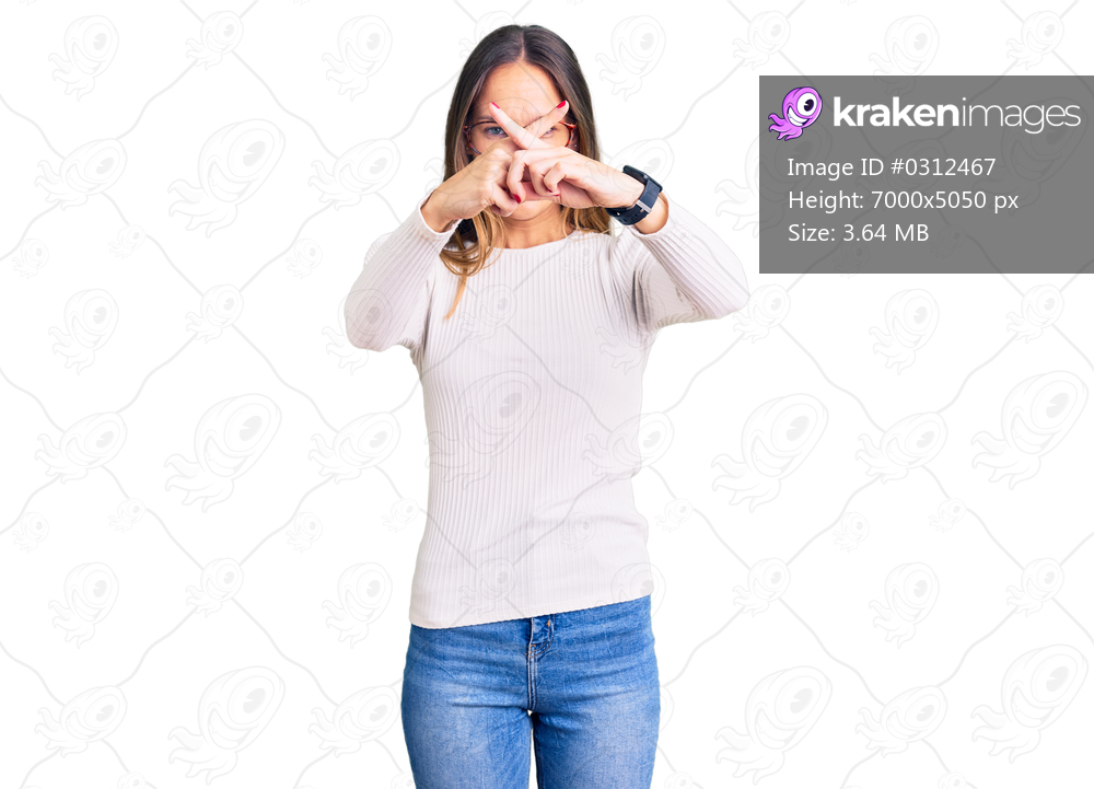 Beautiful brunette young woman wearing casual white sweater and glasses rejection expression crossing fingers doing negative sign 