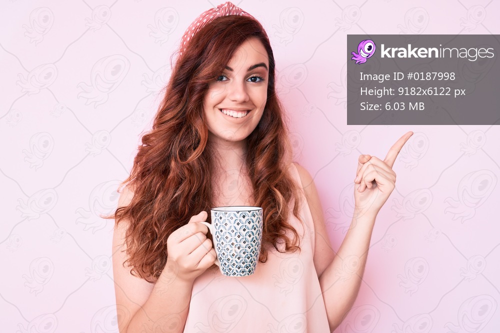 Young beautiful woman holding coffee smiling happy pointing with hand and finger to the side 