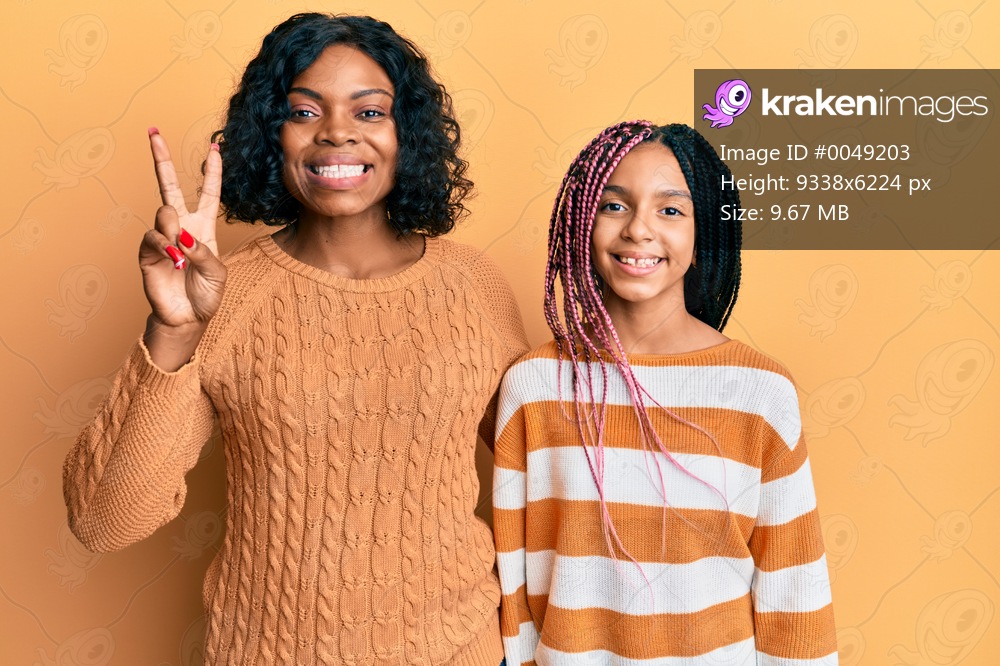 Beautiful african american mother and daughter wearing wool winter sweater showing and pointing up with fingers number two while smiling confident and happy. 