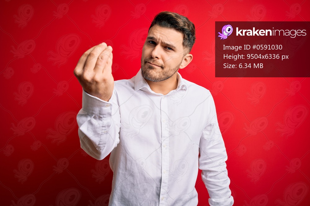 Young business man with blue eyes wearing elegant shirt standing over red isolated background Doing Italian gesture with hand and fingers confident expression