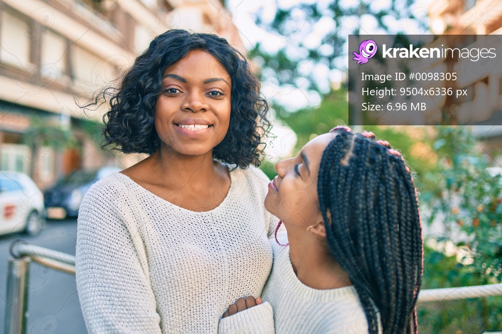 Beautiful african american mother and daughter smiling happy and hugging. Standing with smile on face standing at the city.