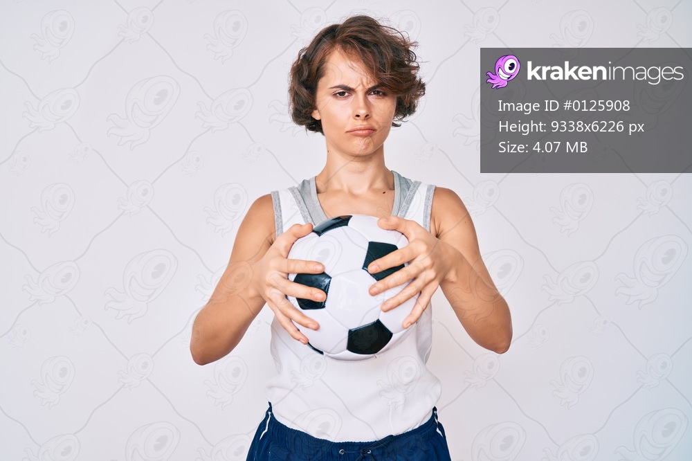 Young hispanic woman holding soccer ball depressed and worry for distress, crying angry and afraid. sad expression. 