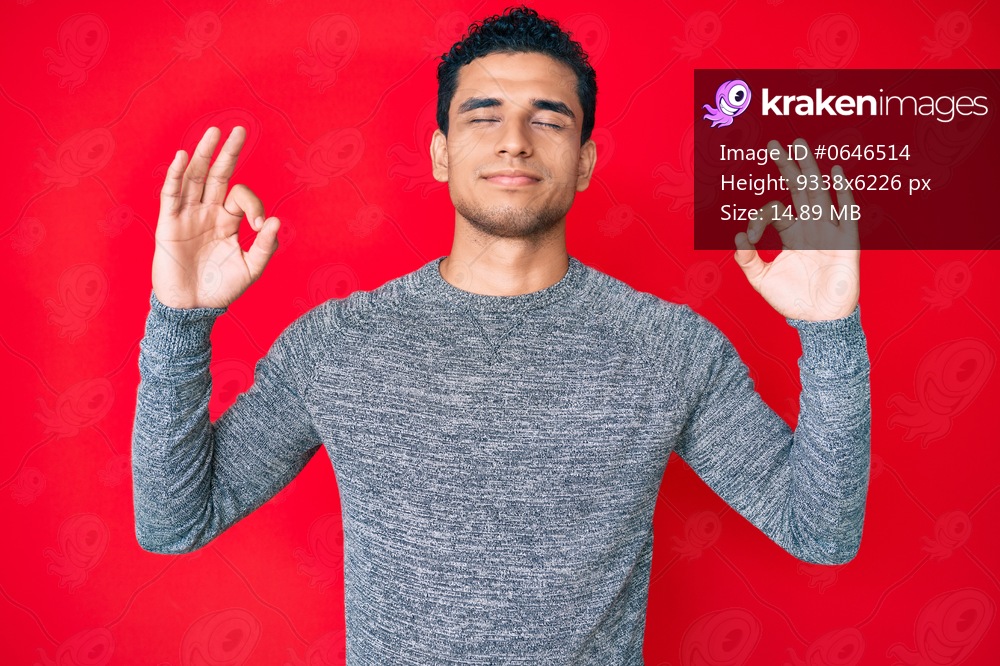 Young handsome hispanic man over red background relax and smiling with eyes closed doing meditation gesture with fingers. yoga concept. 