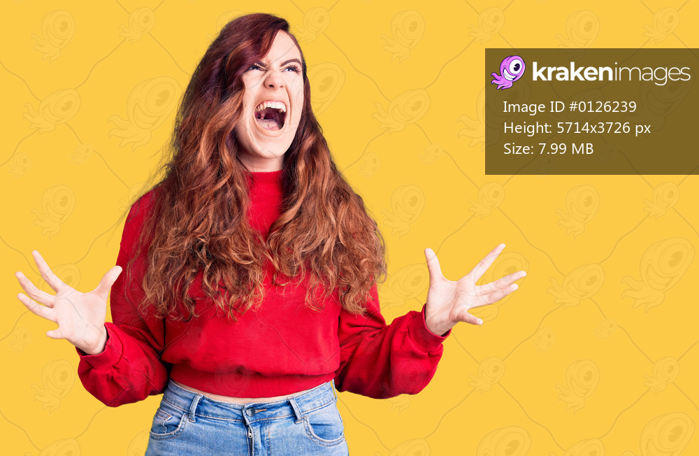 Young beautiful woman wearing casual winter sweater crazy and mad shouting and yelling with aggressive expression and arms raised. frustration concept. 