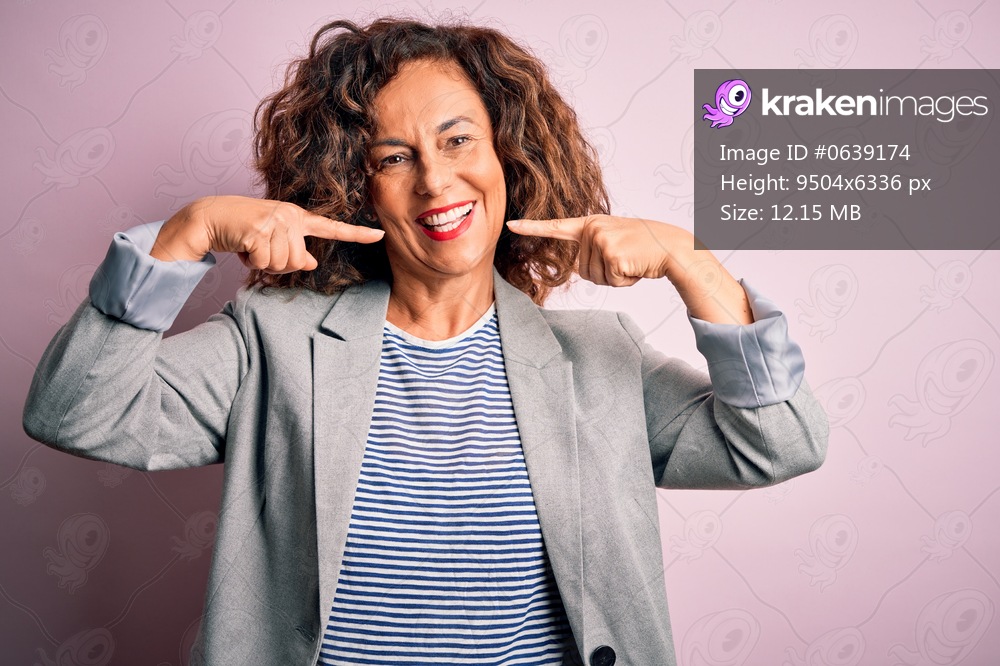 Middle age beautiful businesswoman wearing elegant jacket over isolated pink background smiling cheerful showing and pointing with fingers teeth and mouth. Dental health concept.