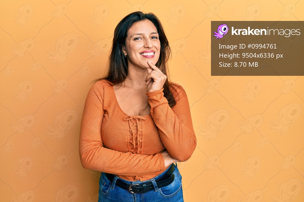 Beautiful hispanic woman wearing casual clothes smiling looking confident at the camera with crossed arms and hand on chin. thinking positive. 