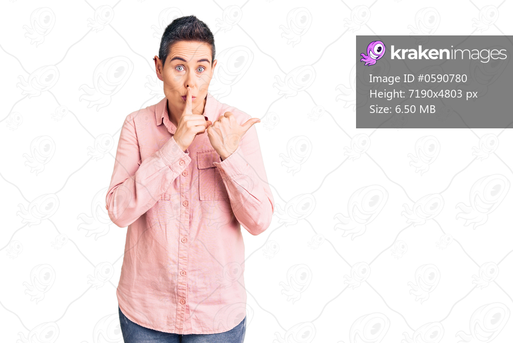 Young woman with short hair wearing casual clothes asking to be quiet with finger on lips pointing with hand to the side. silence and secret concept. 