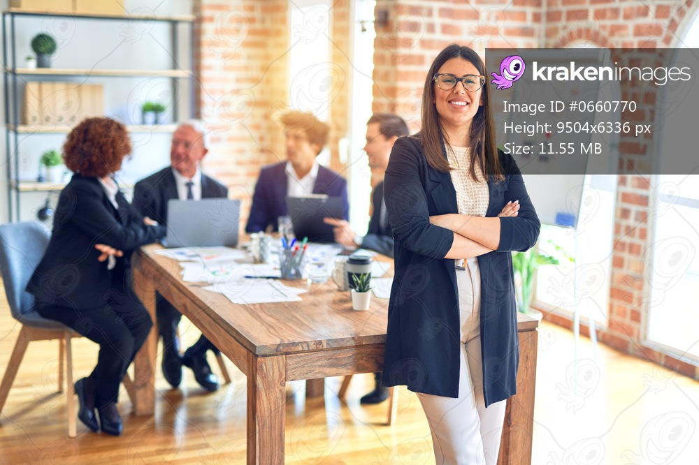 Group of business workers smiling happy and confident working together in a meeting. One of them, standing with smile on face looking at camera at the office.