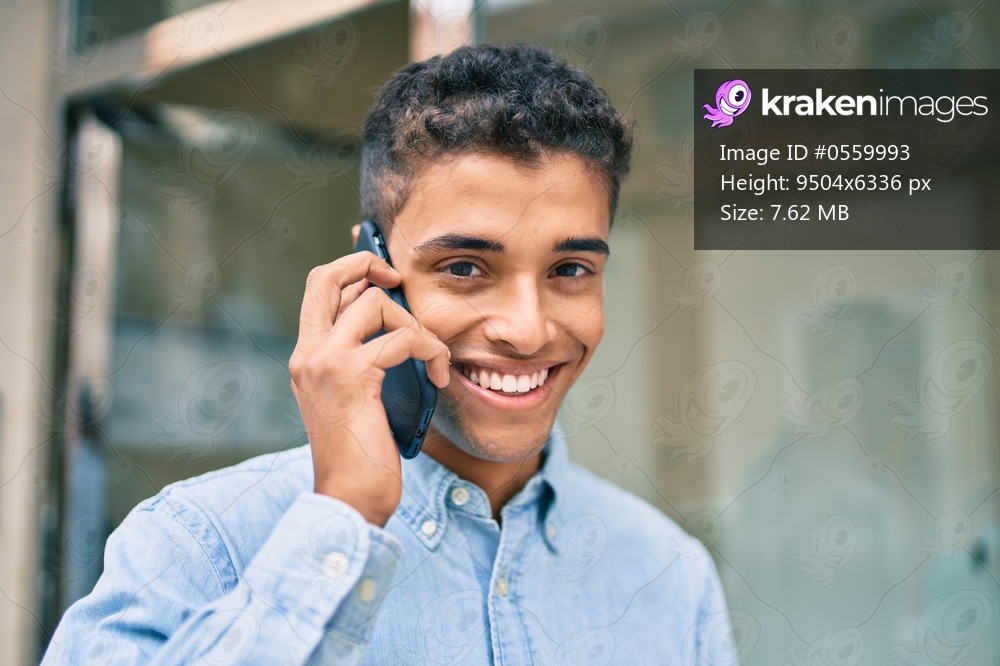 Young latin man smiling happy talking on the smartphone walking at the city.