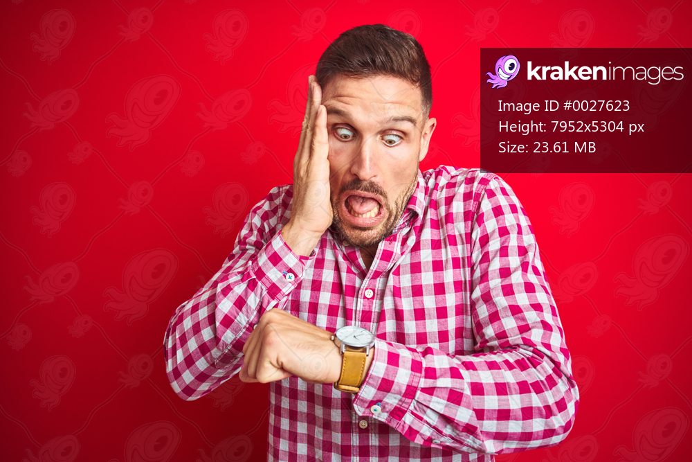 Young handsome man over red isolated background Looking at the watch time worried, afraid of getting late