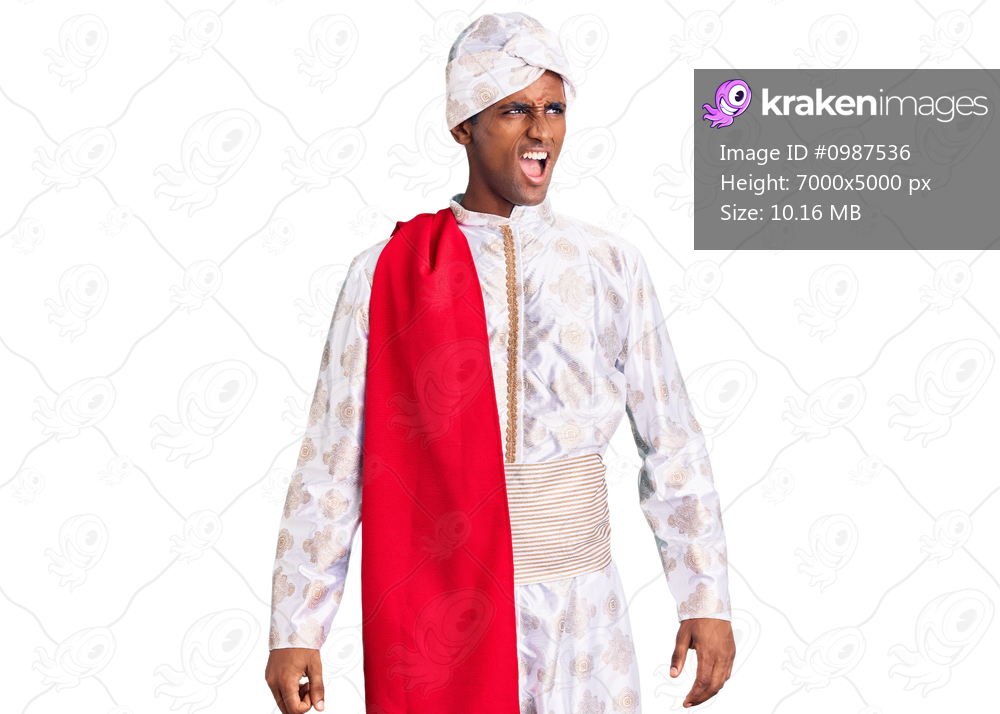 African handsome man wearing tradition sherwani saree clothes angry and mad screaming frustrated and furious, shouting with anger. rage and aggressive concept. 