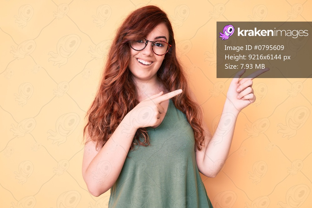 Young beautiful woman wearing casual clothes and glasses smiling and looking at the camera pointing with two hands and fingers to the side. 