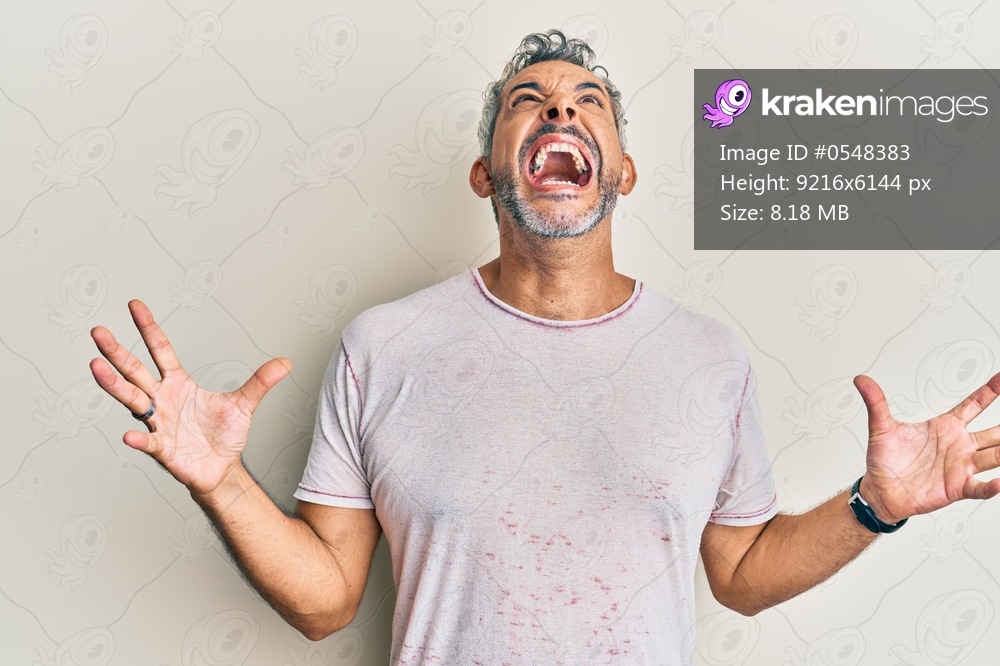 Middle age grey-haired man wearing casual clothes crazy and mad shouting and yelling with aggressive expression and arms raised. frustration concept. 