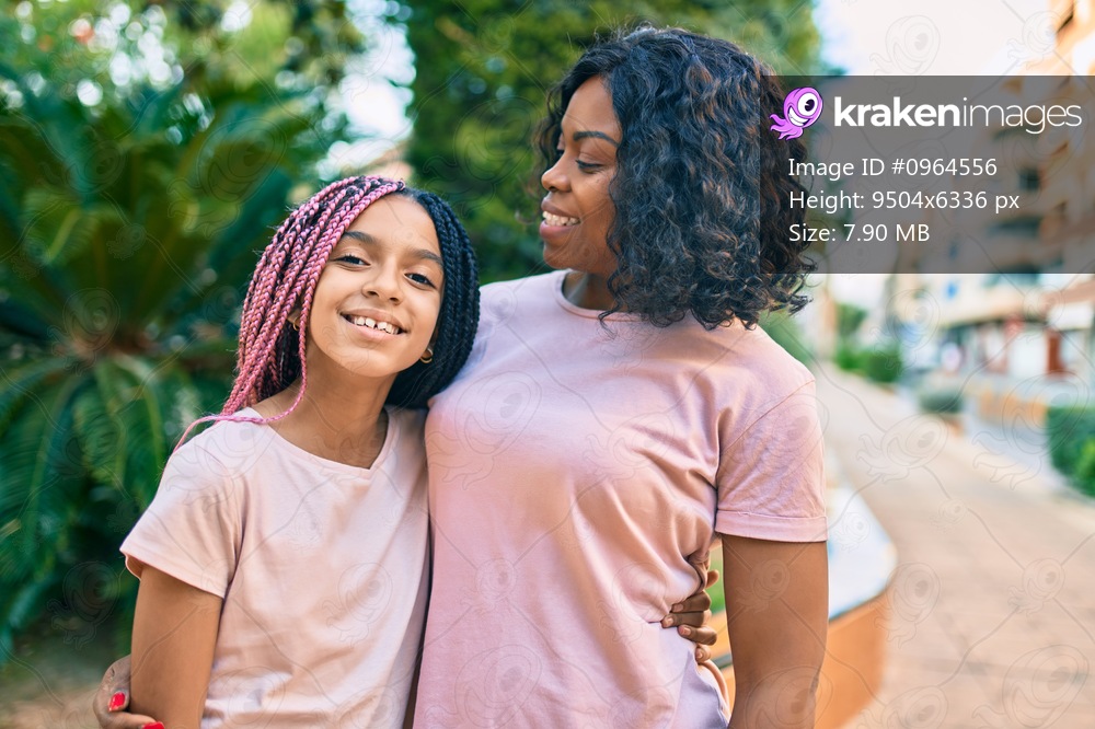 Beautiful african american mother and daughter smiling happy and hugging. Standing with smile on face standing at the park.