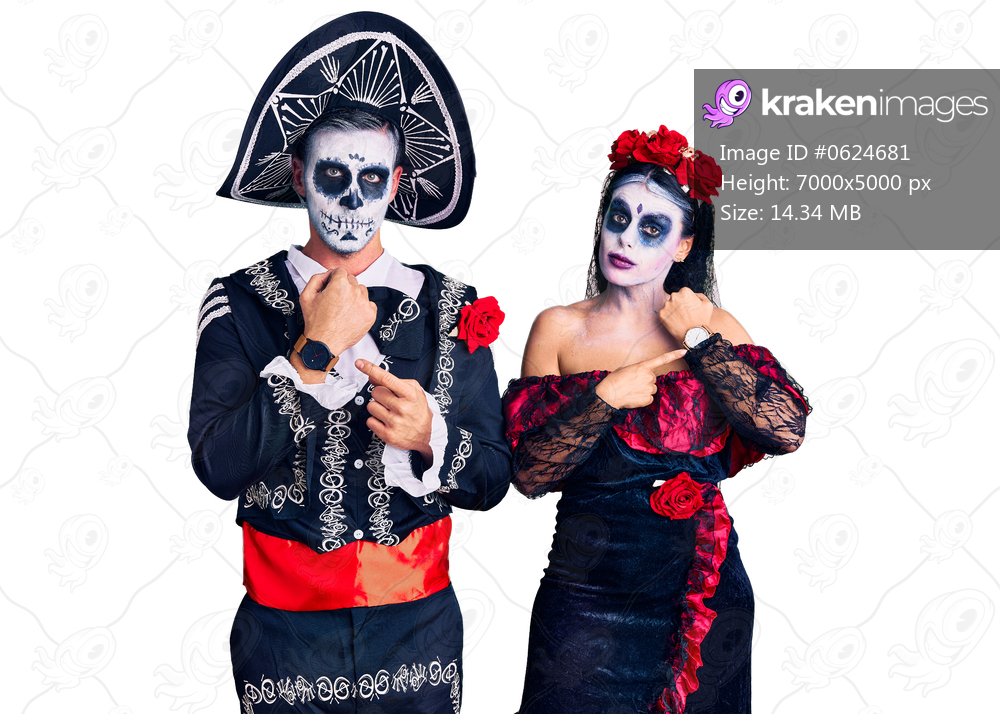 Young couple wearing mexican day of the dead costume over background in hurry pointing to watch time, impatience, looking at the camera with relaxed expression 