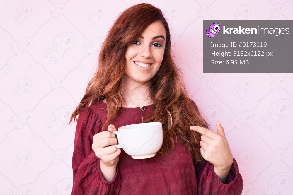 Young beautiful woman holding coffee smiling happy pointing with hand and finger 