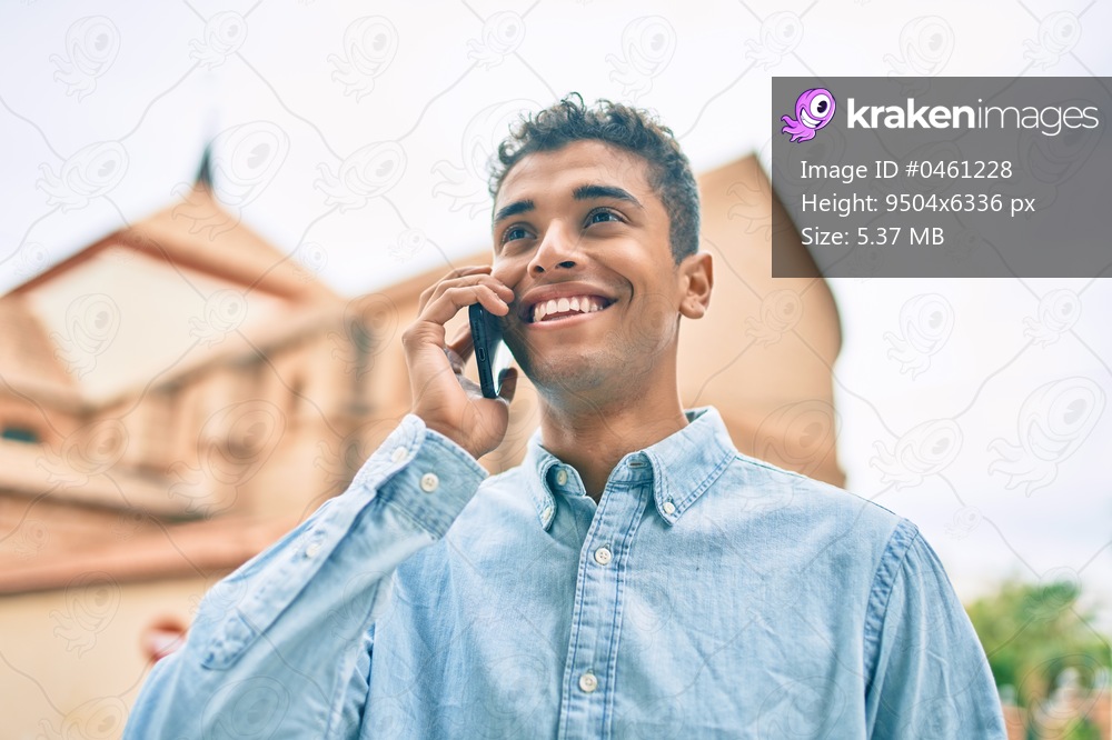 Young latin man smiling happy talking on the smartphone walking at the city.
