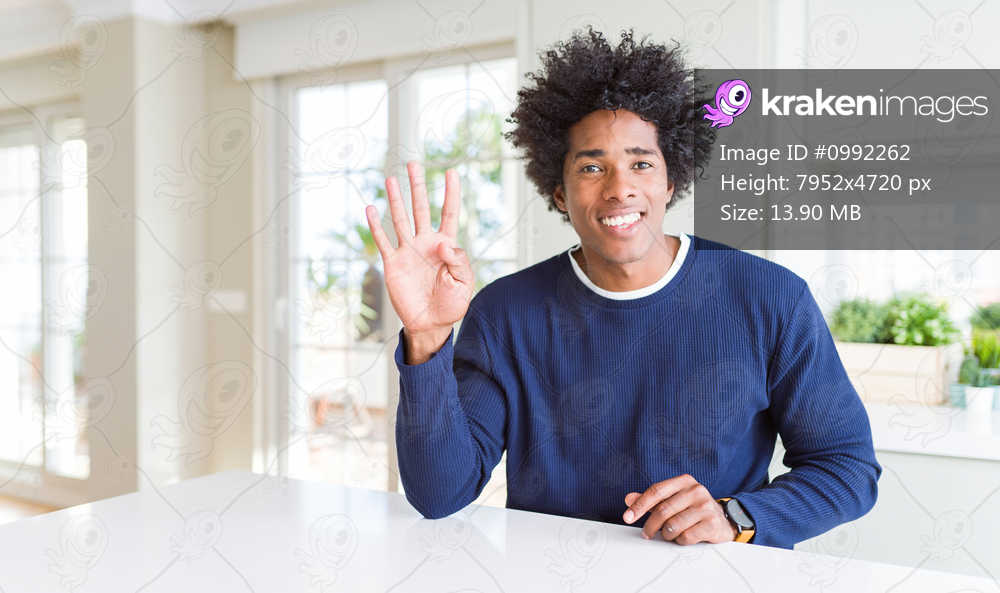 Young african american man wearing casual sweater sitting at home showing and pointing up with fingers number four while smiling confident and happy.