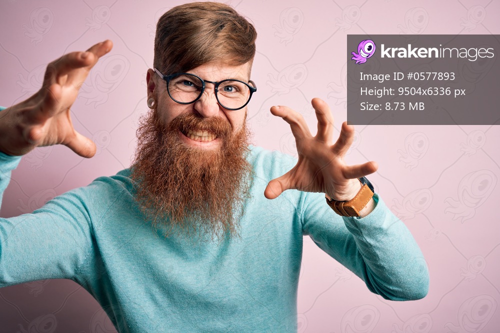 Handsome Irish redhead man with beard wearing glasses over pink isolated background Shouting frustrated with rage, hands trying to strangle, yelling mad