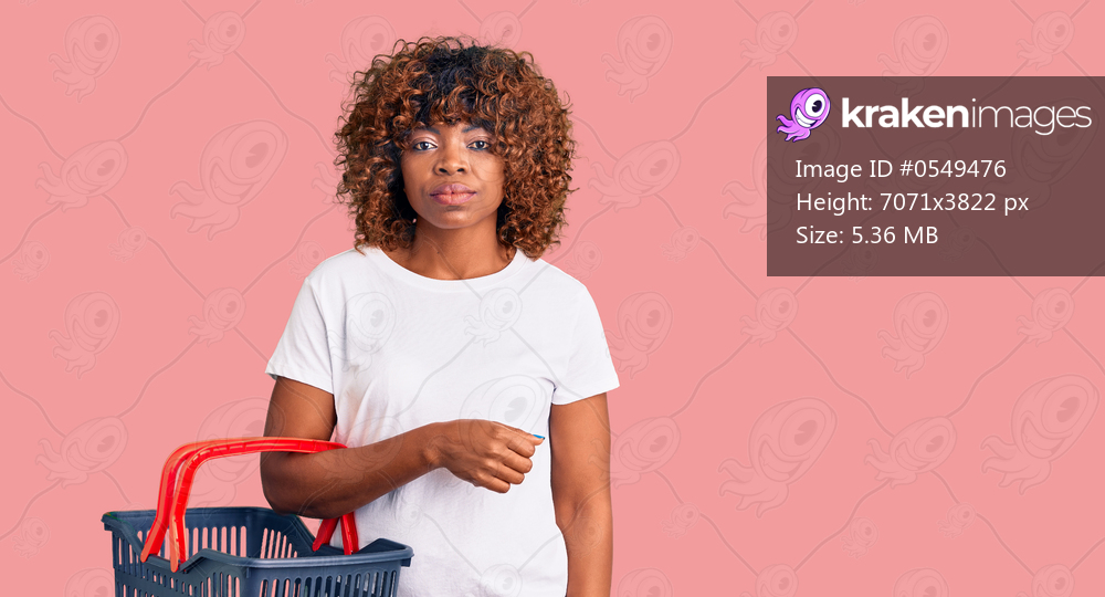 Young african american woman holding supermarket shopping basket thinking attitude and sober expression looking self confident 
