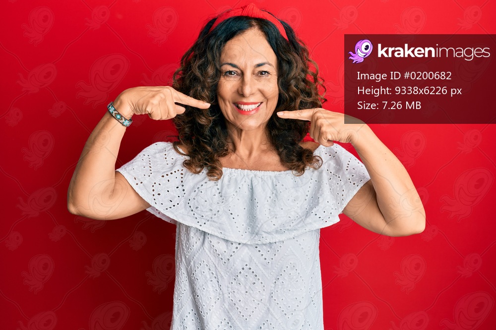 Middle age hispanic woman wearing casual clothes smiling cheerful showing and pointing with fingers teeth and mouth. dental health concept. 
