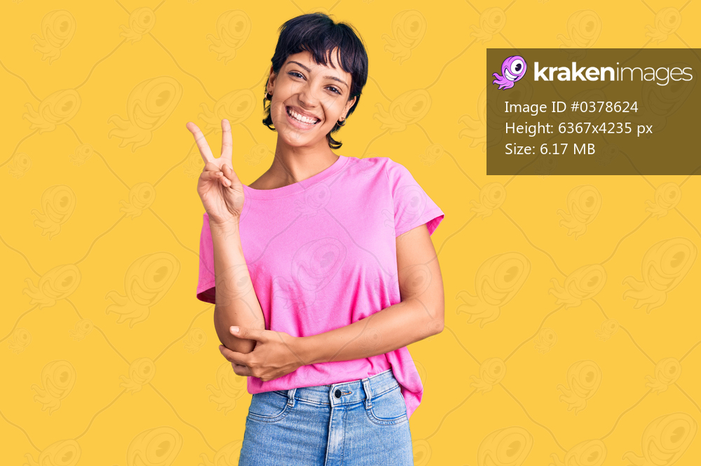 Young brunette woman with short hair wearing casual clothes smiling with happy face winking at the camera doing victory sign. number two. 