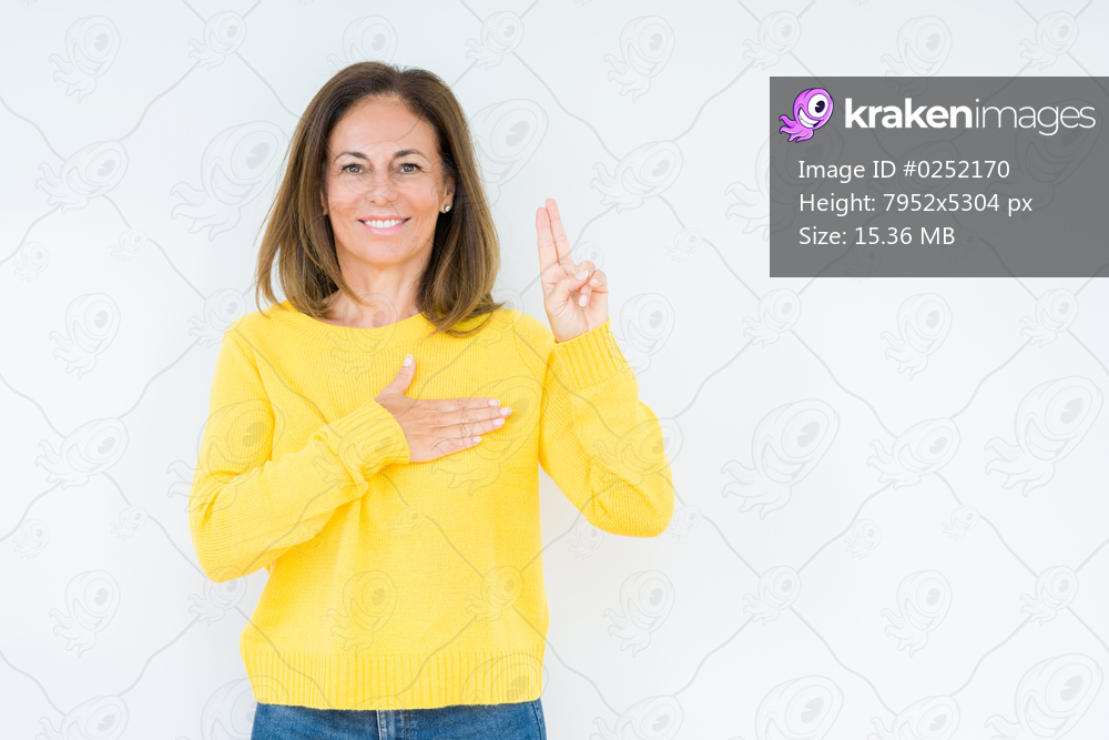 Beautiful middle age woman wearing yellow sweater over isolated background Swearing with hand on chest and fingers, making a loyalty promise oath