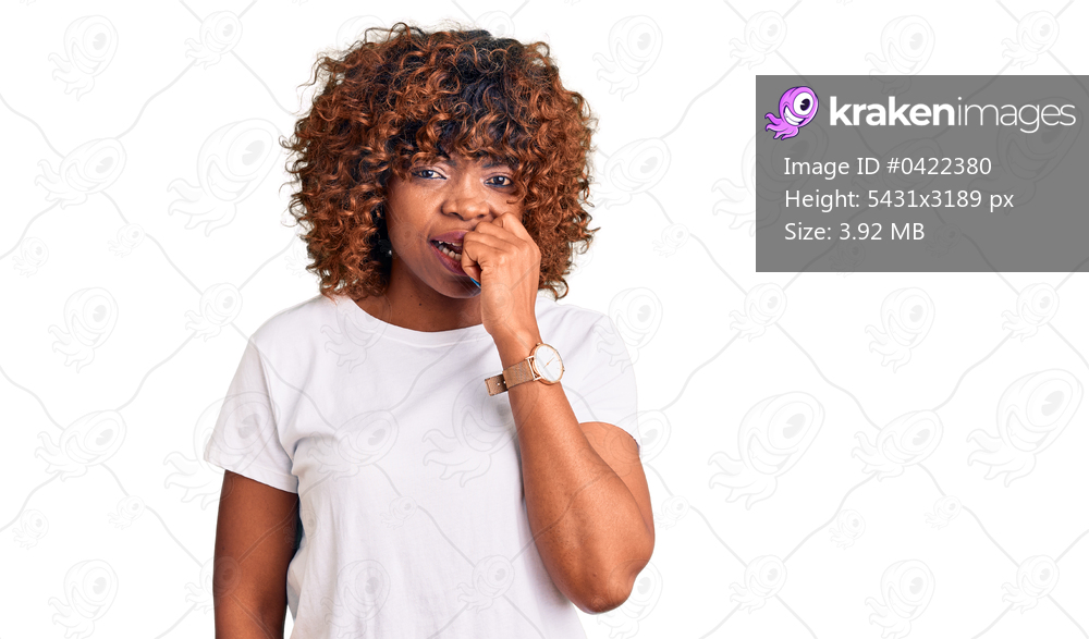 Young african american woman wearing casual white tshirt looking stressed and nervous with hands on mouth biting nails. anxiety problem. 