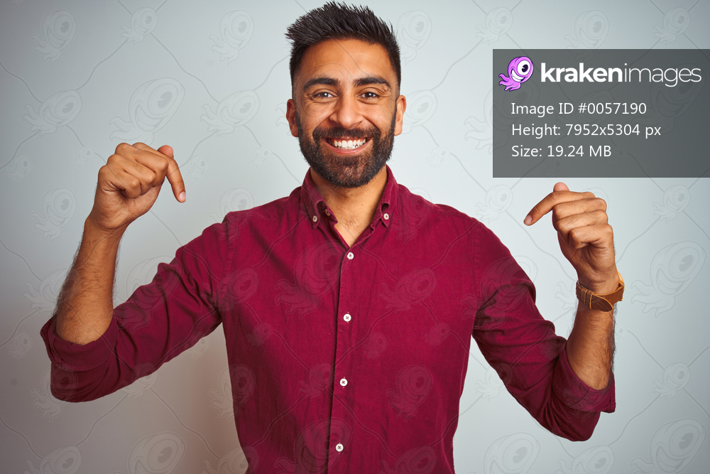 Young indian man wearing red elegant shirt standing over isolated grey background looking confident with smile on face, pointing oneself with fingers proud and happy.