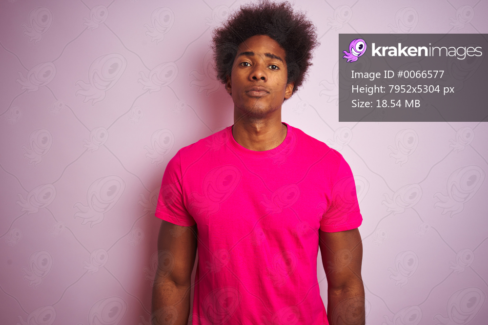 Young american man with afro hair wearing t-shirt standing over isolated pink background with serious expression on face. Simple and natural looking at the camera.
