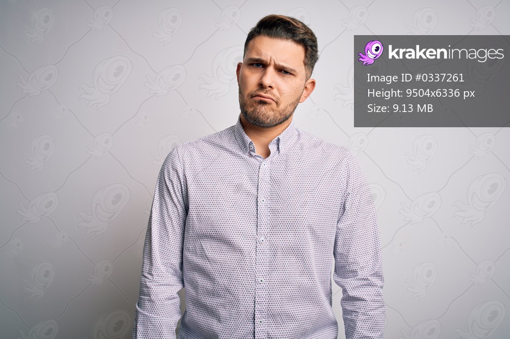Young business man with blue eyes standing over isolated background skeptic and nervous, frowning upset because of problem. Negative person.
