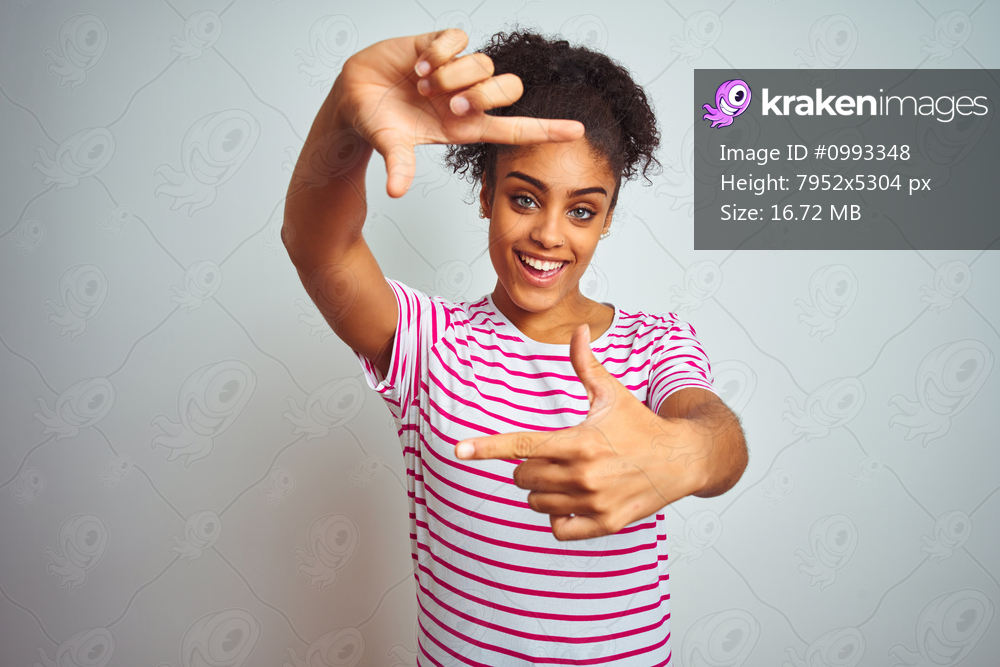 African american woman wearing casual pink striped t-shirt over isolated white background smiling making frame with hands and fingers with happy face. Creativity and photography concept.