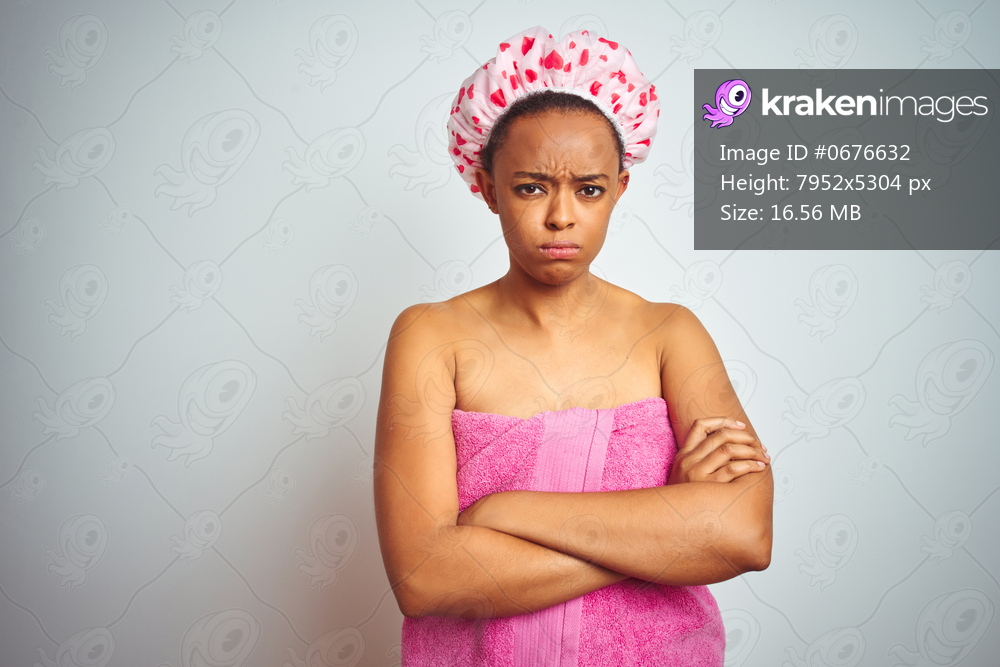African american woman wearing pink shower towel after bath over isolated background skeptic and nervous, disapproving expression on face with crossed arms. Negative person.