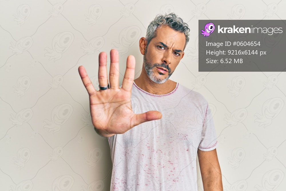 Middle age grey-haired man wearing casual clothes doing stop sing with palm of the hand. warning expression with negative and serious gesture on the face. 