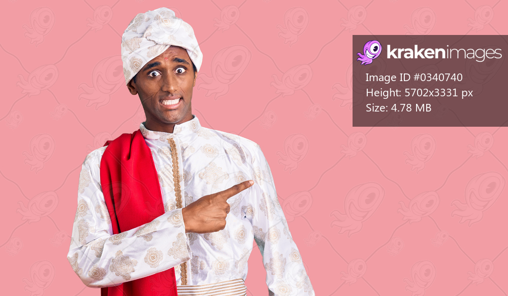 African handsome man wearing tradition sherwani saree clothes pointing aside worried and nervous with forefinger, concerned and surprised expression 