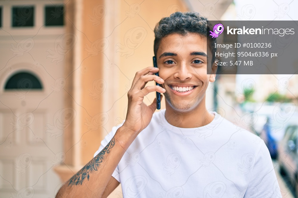 Young latin man smiling happy talking on the smartphone walking at the city.