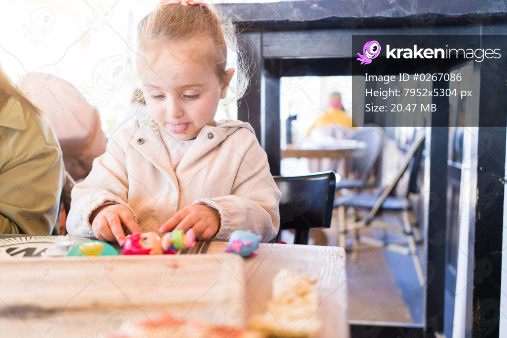 Beautiful toddler child girl sitting on baby highchair  playing with toys on the table