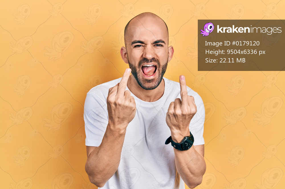 Young bald man wearing casual white t shirt showing middle finger doing fuck you bad expression, provocation and rude attitude. screaming excited 