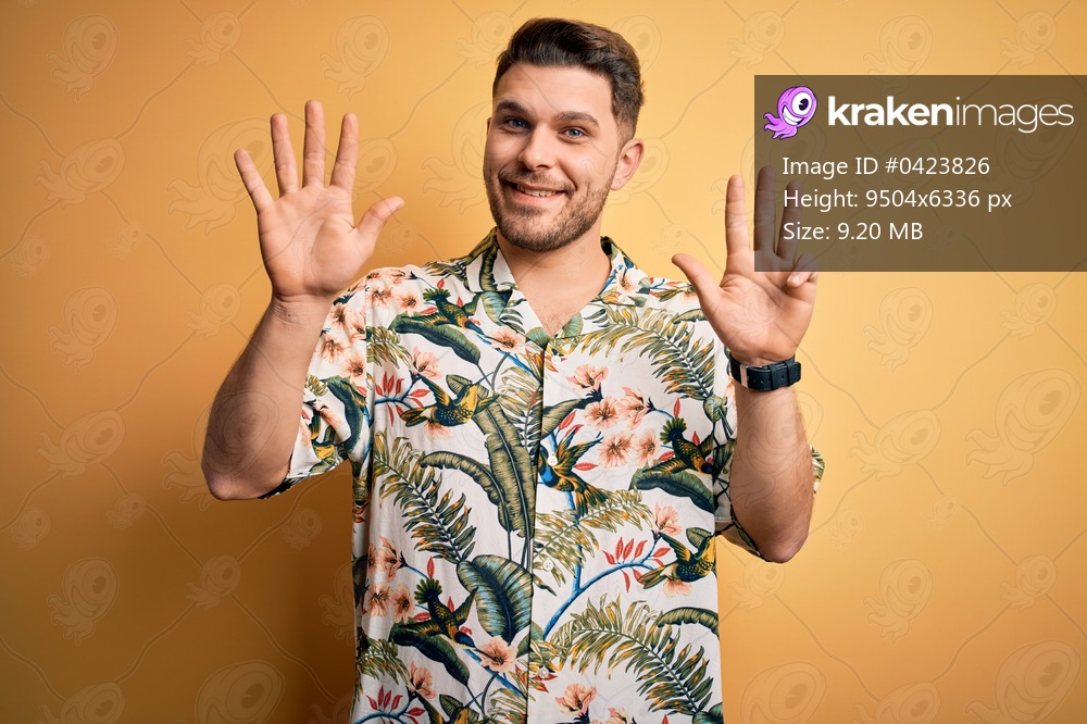 Young man with blue eyes on vacation wearing floral summer shirt over yellow background showing and pointing up with fingers number nine while smiling confident and happy.