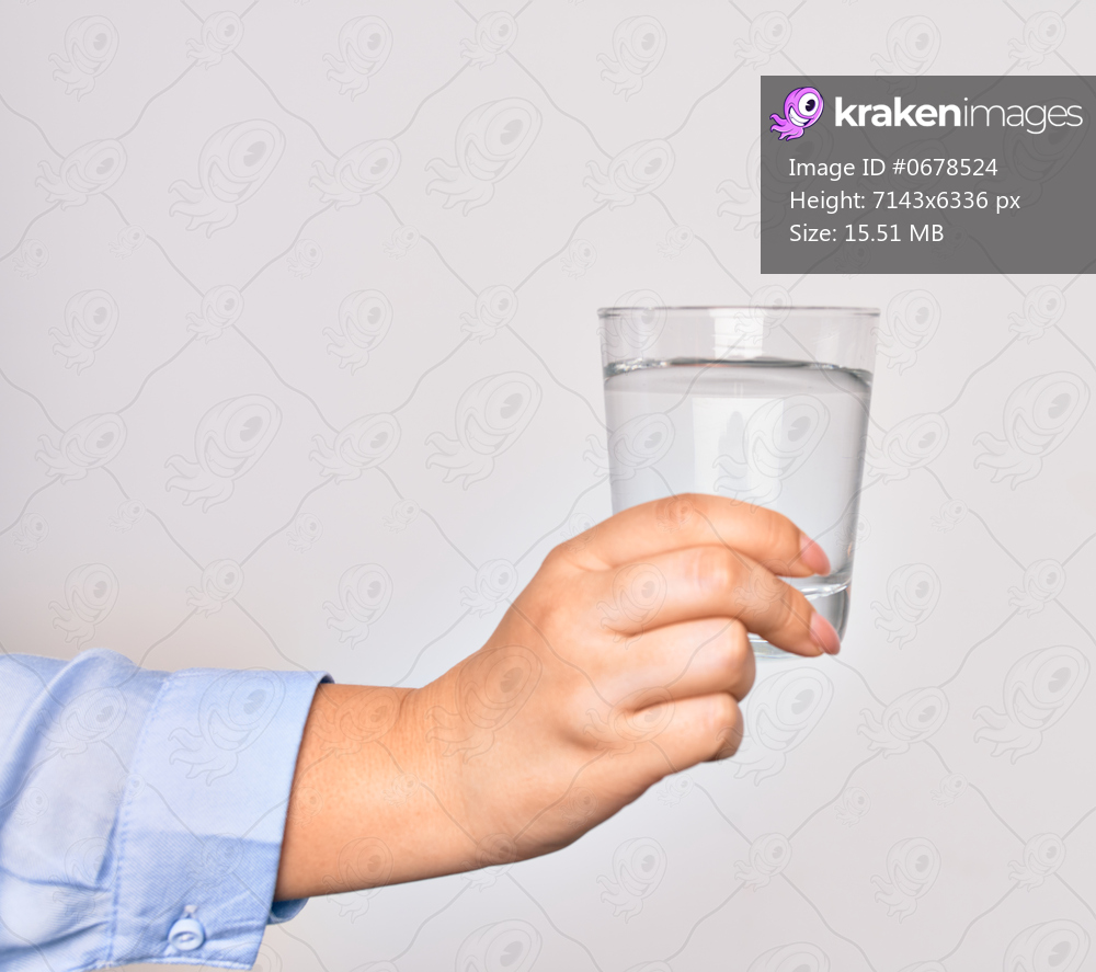 Hand of caucasian young woman holding glass of water over isolated white background