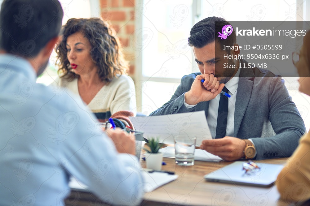 Group of business workers working together. Sitting on desk reading documents at the office