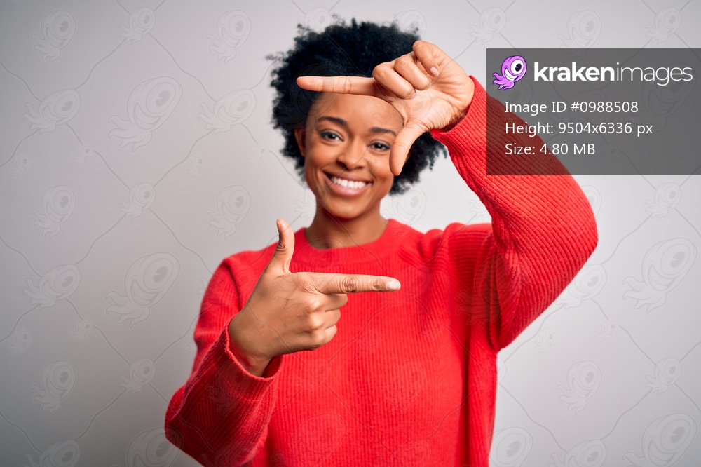 Young beautiful African American afro woman with curly hair wearing red casual sweater smiling making frame with hands and fingers with happy face. Creativity and photography concept.