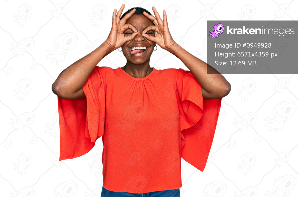 Young african american woman wearing casual clothes doing ok gesture like binoculars sticking tongue out, eyes looking through fingers. crazy expression. 