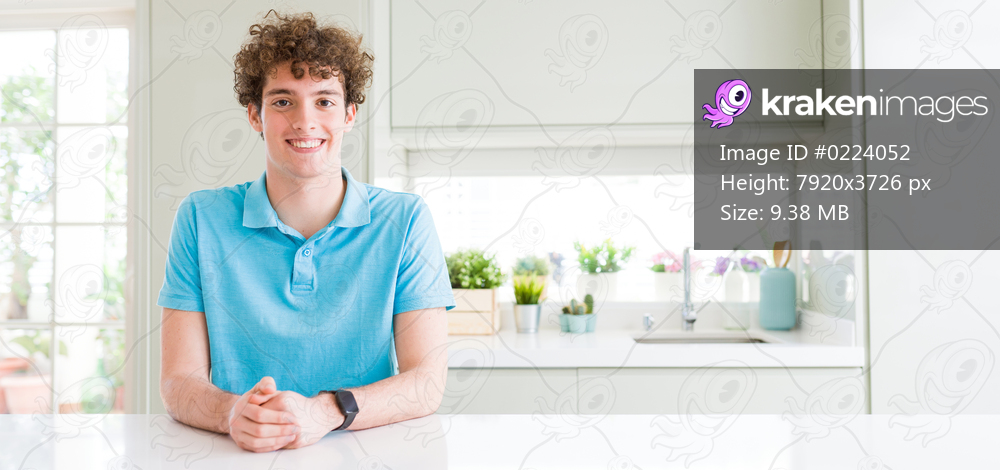 Wide shot of young handsome man at home with a happy and cool smile on face. Lucky person.
