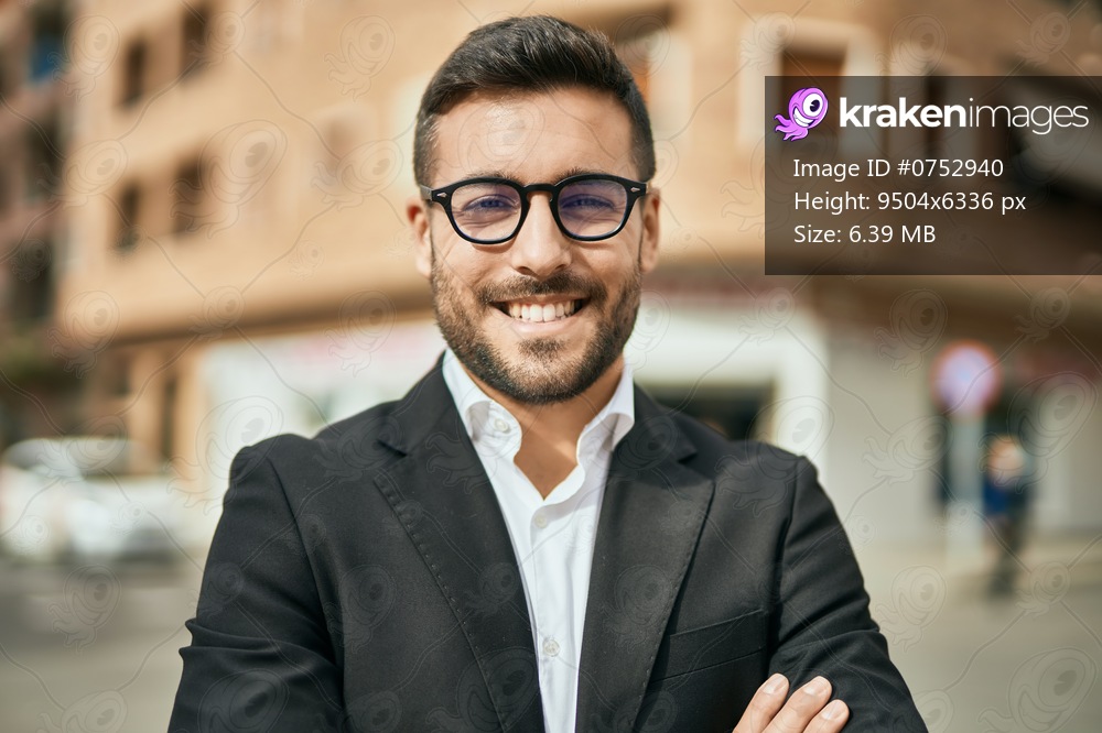 Young hispanic businessman with arms crossed smiling happy at the city.
